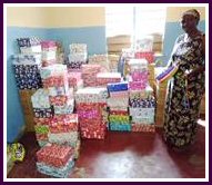 Photograph: Woman posing with shoe boxes and gifts donated by Lutterworth Rotary.
